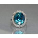 A blue-green zircon ring, the large oval-cut stone of approx. 8.5 carats, set within a border of