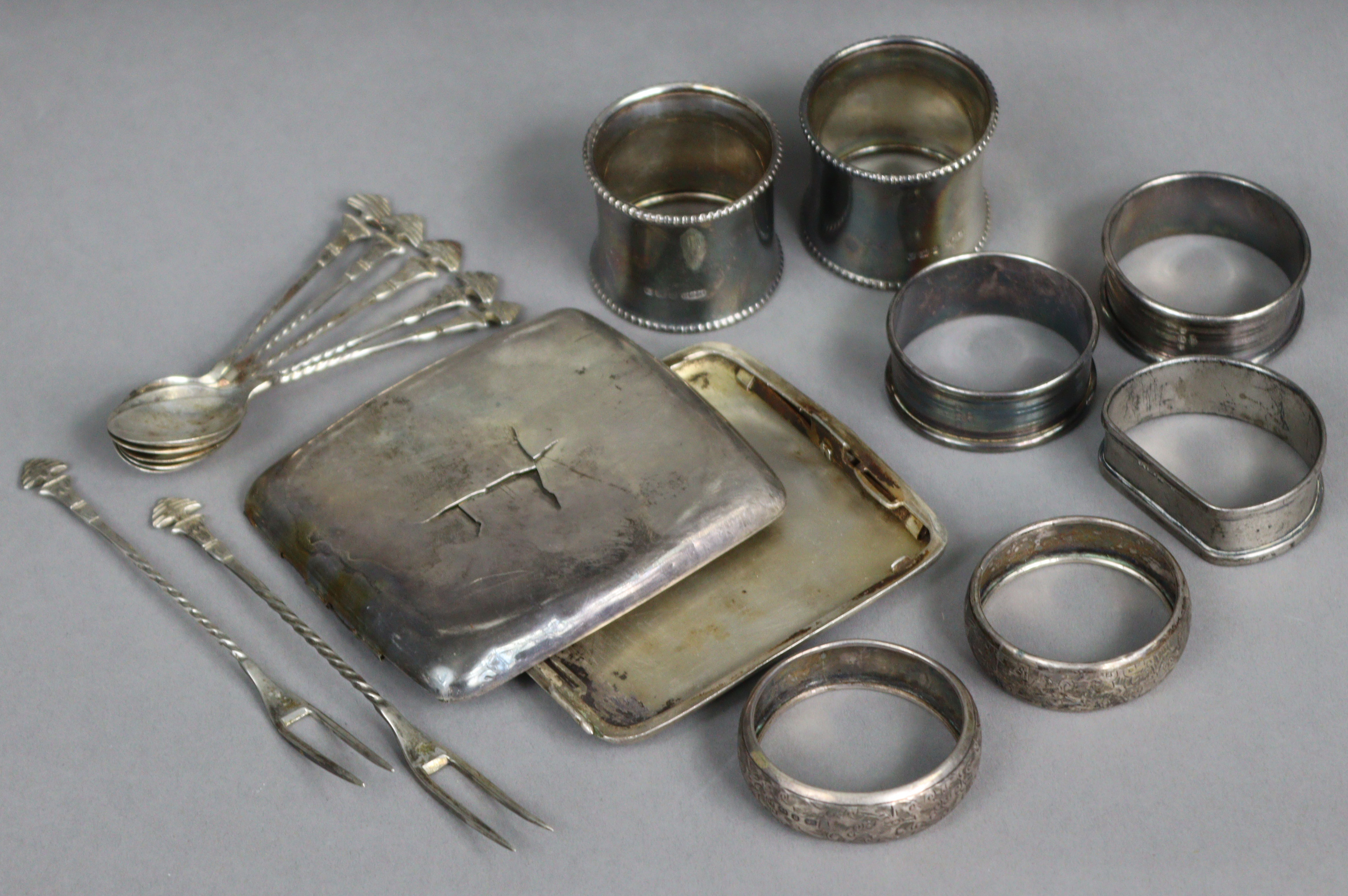 Seven various silver napkin rings; a silver cigarette case (w.a.f.); & a set of foreign coffee