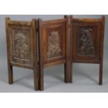 An early 20th century Arts & Crafts carved oak firescreen, depicting two terriers looking towards