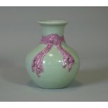 A Chinese porcelain celadon-glazed vase of squat baluster form, with pink tied ribbon-bow around the