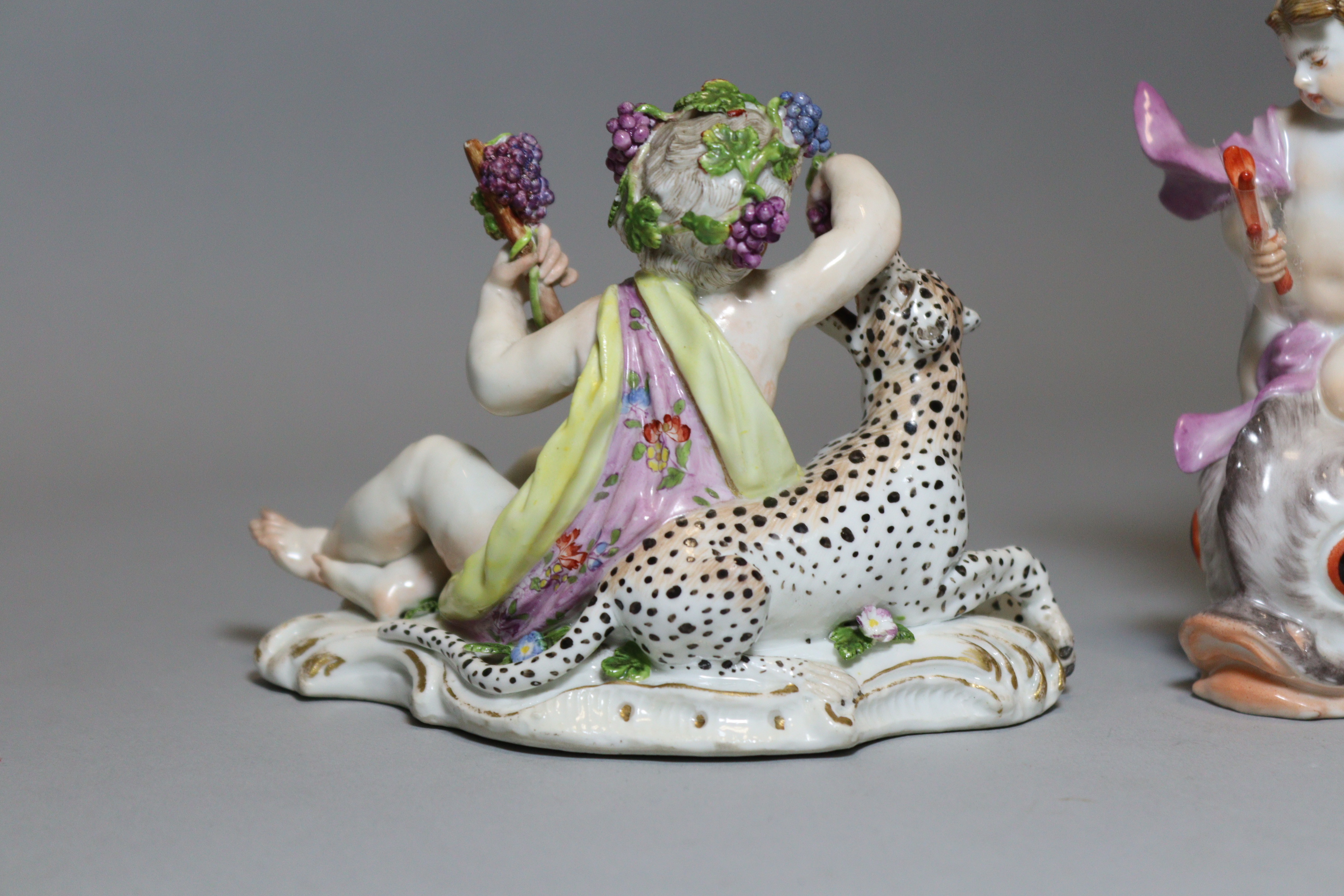 An 18th century Meissen porcelain figure of a reclining putto feeding grapes to a leopard, on scroll - Image 3 of 5