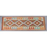 A Choli kilim runner of ivory ground with central row of four lozenges within multiple geometric