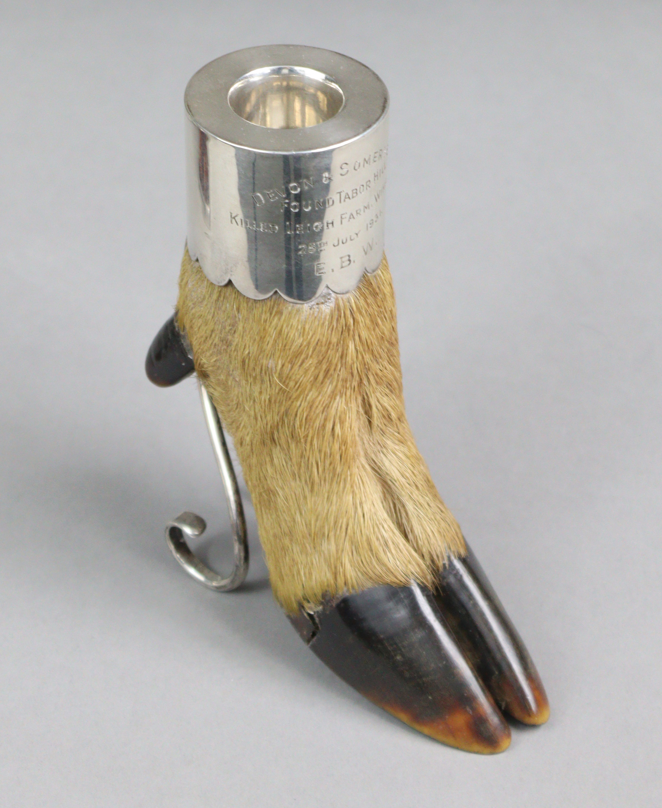 A deer’s foot mounted as a silver match holder, with striker to the rear, supported by two scroll