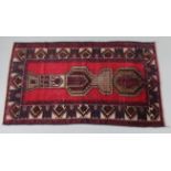 A Baluchi rug of madder ground with central geometric design surrounded by multiple borders, 33”