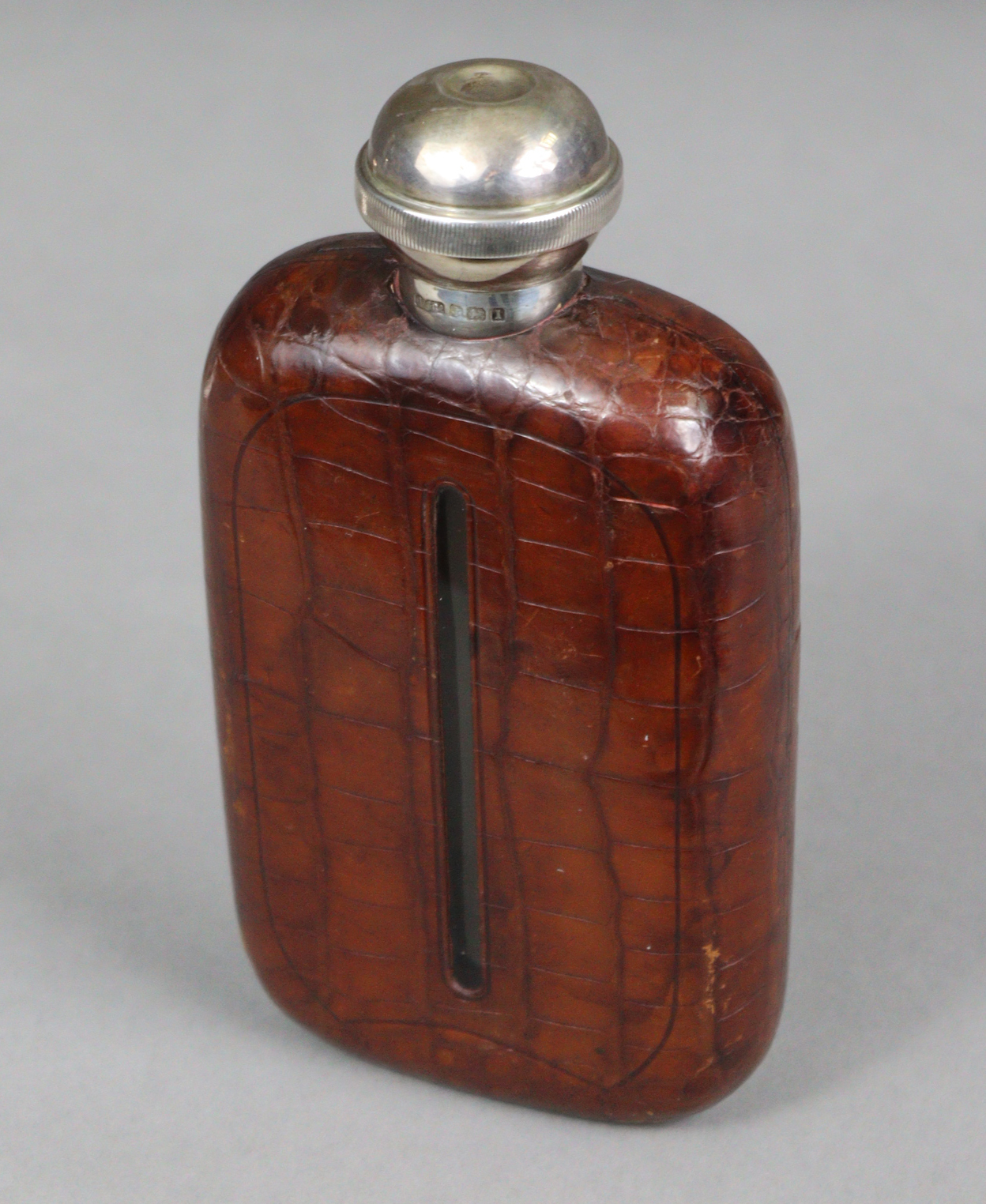 A George V NOVELTY SILVER-MOUNT GLASS SPIRIT FLASK, covered in tan crocodile skin case, the silver