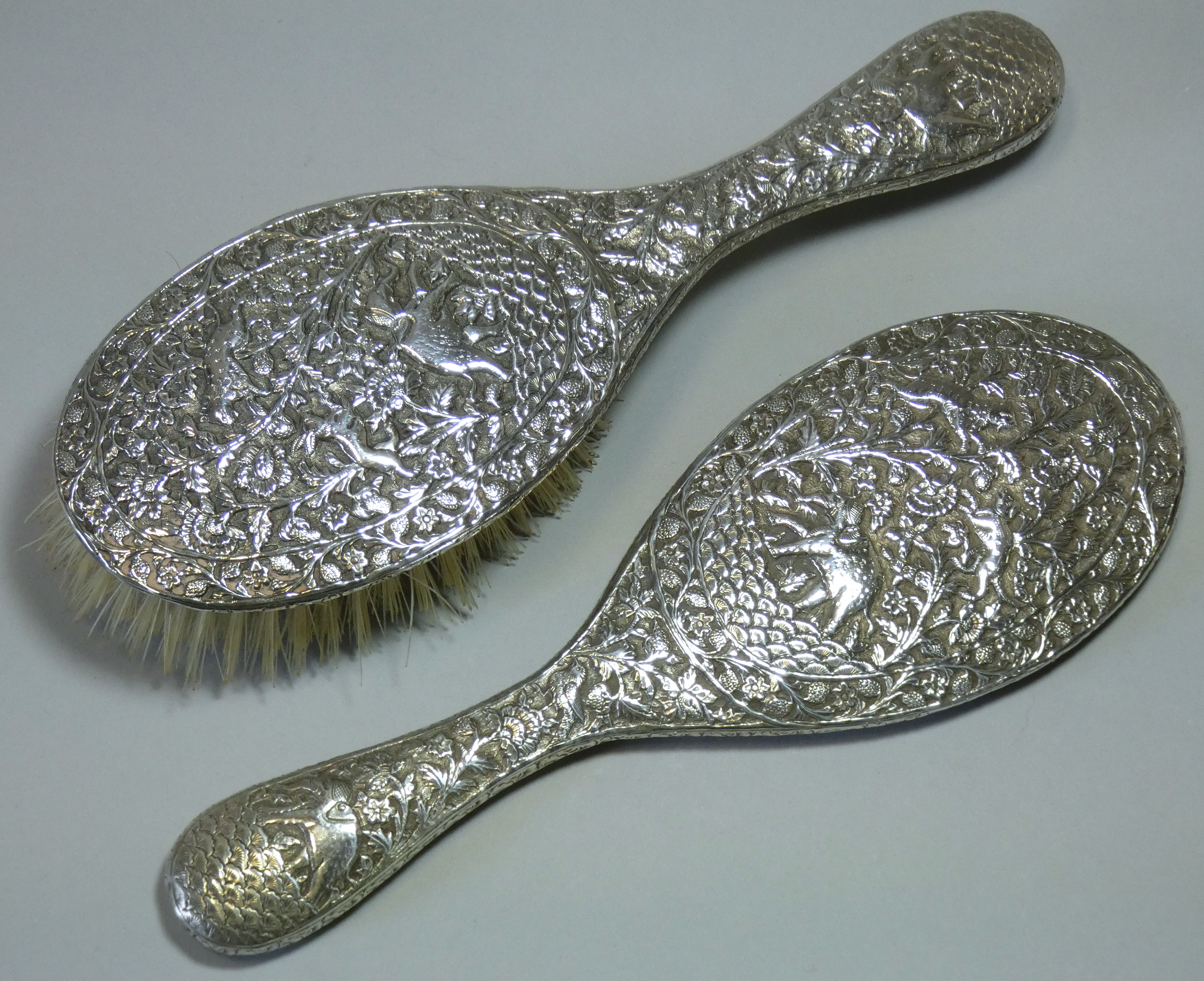 A late 19th/early 20th century Indian silver-backed hand mirror & matching hairbrush, with all-