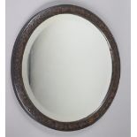 A circular wall mirror in oak frame with carved oriental decoration, bears label for “J. L.