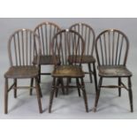 A set of five oak spindle-back dining chairs with hard seats, & in round tapered legs with spindle