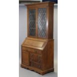 A late 19th/early 20th century oak bureau-bookcase with moulded cornice above a pair of leaded