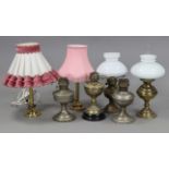 An Edwardian brass embossed oil table lamp, 21¾” high; together with four other oil lamps; & a
