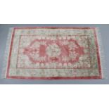 A Chinese part silk rug of pink ground with central floral medallion surrounded by different