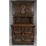 A 17th century-style carved oak tall cabinet, the upper part enclosed by a pair of panel doors above