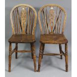 A pair of Windsor-style wheel-back dining chairs with hard seats, & on turned legs with spindle