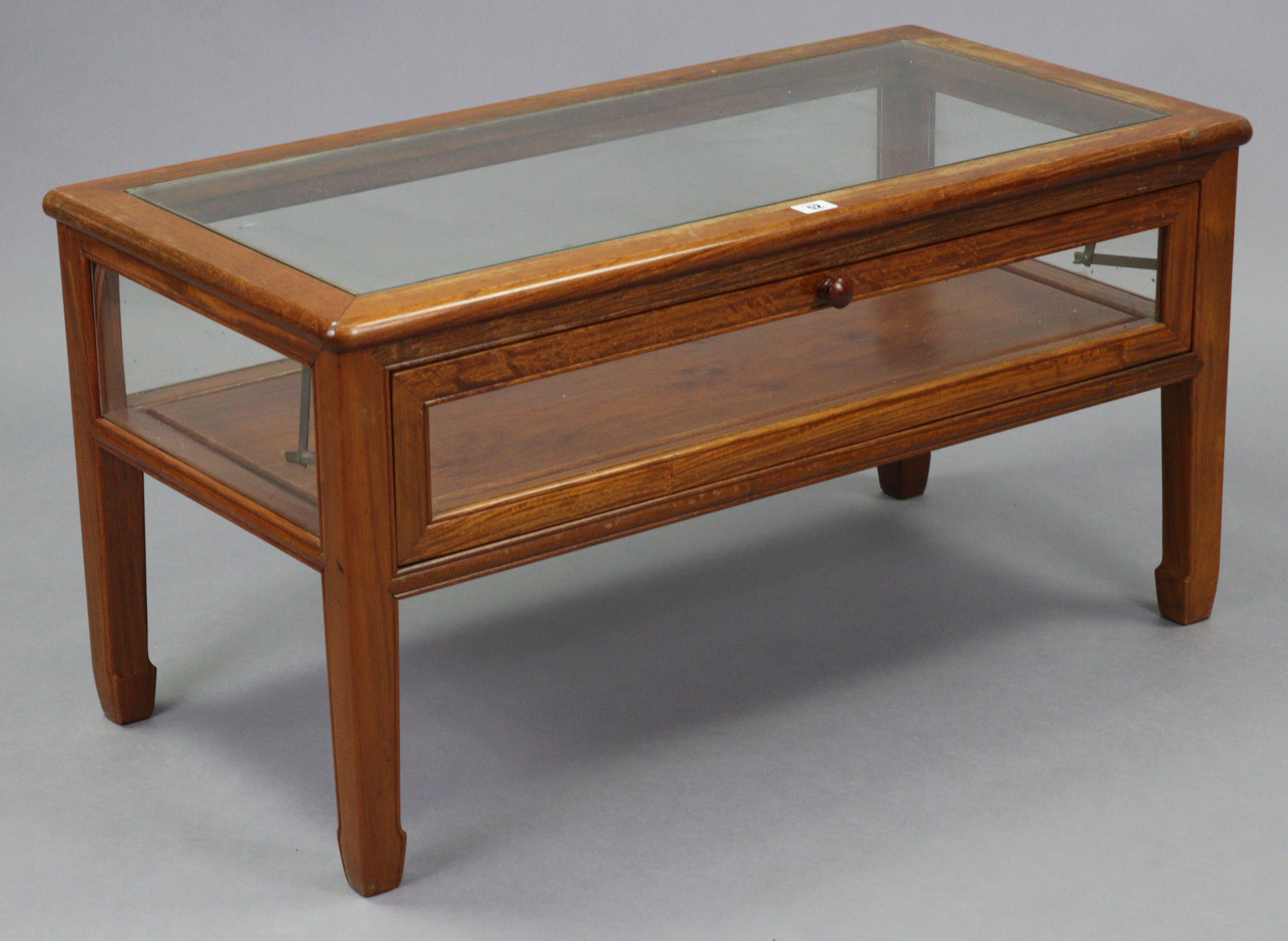 A Chinese rosewood display-top coffee table inset plate-glass to the rectangular top, enclosed by