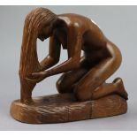 A carved wooden ornament in the form of a kneeling female figure holding her hair in her hands