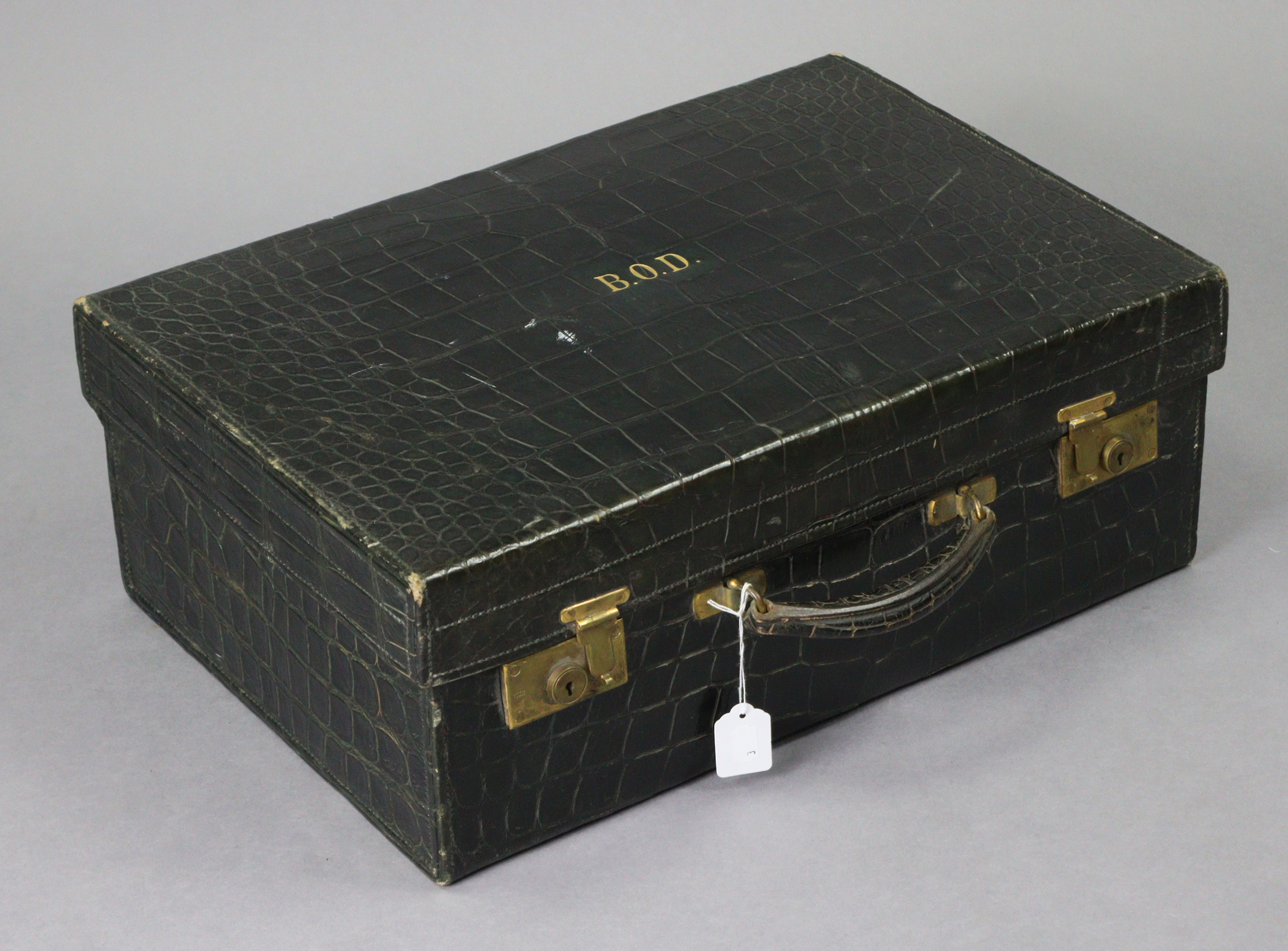 A late 19th/early 20th century dark green finish crocodile-skin suitcase with brass twin-lever