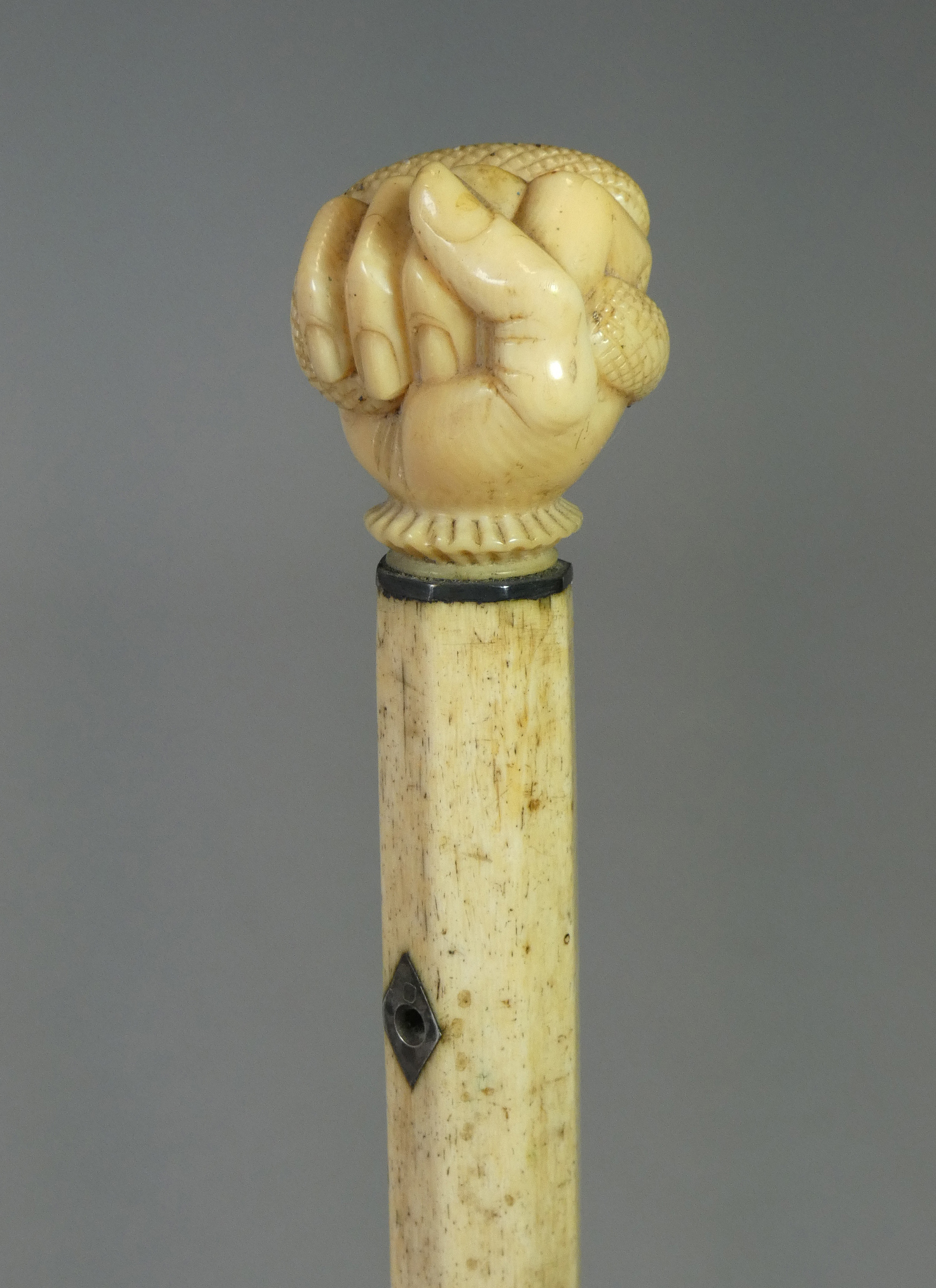 A 19th century whale jaw-bone & ivory-handled walking stick carved with a fist clutching a