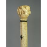 A 19th century whale jaw-bone & ivory-handled walking stick carved with a fist clutching a