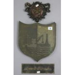 A 1920s bronzed shield-shaped wall plaque with industrial motifs, 11¼” x 12½”; a painted cast-iron
