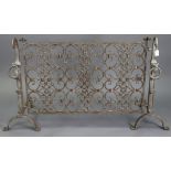 A wrought-iron fire screen with dragon-head ring finials to each fire-dog, 42” wide x 31” high.