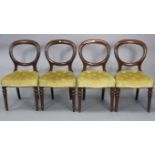 A set of four late Victorian mahogany balloon-back dining chairs with padded seats, & on turned