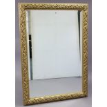 A large gilt frame rectangular wall mirror with raised foliate border, & inset bevelled plate, 54” x