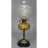 A Victorian brass oil table lamp with amber tinted glass reservoir, & with an etched glass