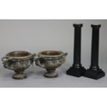 A pair of bronzed circular two-handled vases each with raised mask design & on a round pedestal