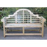 A Lutyen’s style wooden slatted garden bench with scroll arms & on square supports, 65½” wide x 40½”