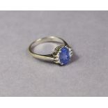 A SAPPHIRE RING, the oval-cut stone weighing approx. 2.8 carats, trios of small diamonds to each