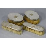 A pair of George V silver-backed oval hair brushes; & a pair of matching clothes brushes, each