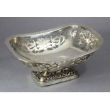 A silver cake basket of curved rectangular shape, with rounded corners & pierced leaf-scroll