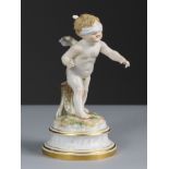 A Meissen porcelain standing figure of ‘Cupid Blindfolded’, on round simulated marble socle with