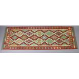 A Chobi kilim runner with repeating multicoloured geometric design within a narrow border, 26”