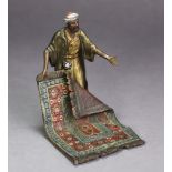 AN AUSTRIAN COLD-PAINTED BRONZE FIGURE OF A CARPET SELLER, standing with his left arm