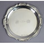 A George V silver waiter with raised border & shaped rim, the centre engraved with two monograms &