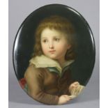 A BERLIN PORCELAIN OVAL PORTRAIT PLAQUE, finely painted with a young boy holding a picture book,