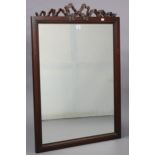 A large rectangular wall mirror in a simulated wooden frame, & with a ribbon-bow surmount, 39” x