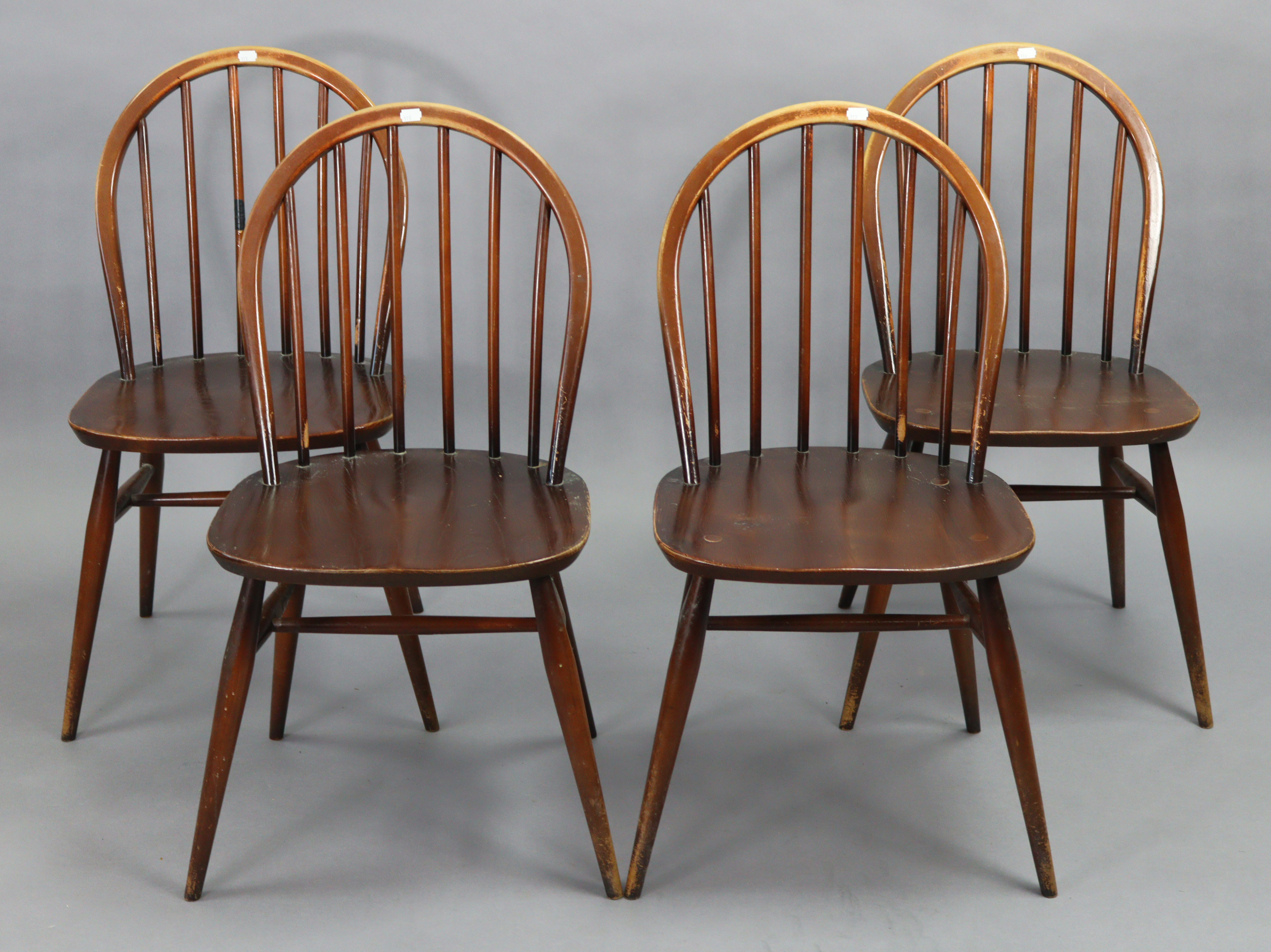 A set of four Ercol spindle-back dining chairs with hard seats, & on round tapered legs with spindle