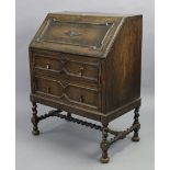 A 1930’s oak bureau with a fitted interior enclosed by a fall-front above two long drawers, & on