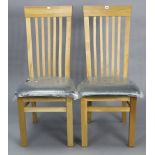A pair of light oak rail-back dining chairs with padded seats, & on square legs with plain