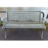A green painted cast-iron & wooden slatted garden bench on pierced & shaped end supports, 50¾”