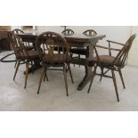 An Ercol dark oak draw leaf dining table, raised on opposing vase shaped ends and platform feet 29.