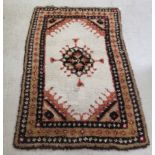 A shaggy woollen rug, decorated with stylised designs, on a cream coloured,