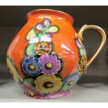 A Carlton Ware orange lustre glazed and gilded bulbous jug with a loop handle and floral decoration