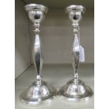 A pair of loaded silver candlesticks with vase shaped sockets,