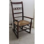 A George III walnut and elm framed country made bar back open arm rocking chair with a woven cane