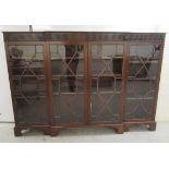 An Edwardian mahogany breakfront bookcase with a fluted frieze, over four astragal glazed doors,