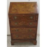 A 1930s walnut and mahogany bureau with a fall front, over four graduated drawers,