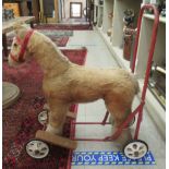 A 'vintage' Tri-ang push-along, plush covered toy horse, on a red painted iron frame with footrests,